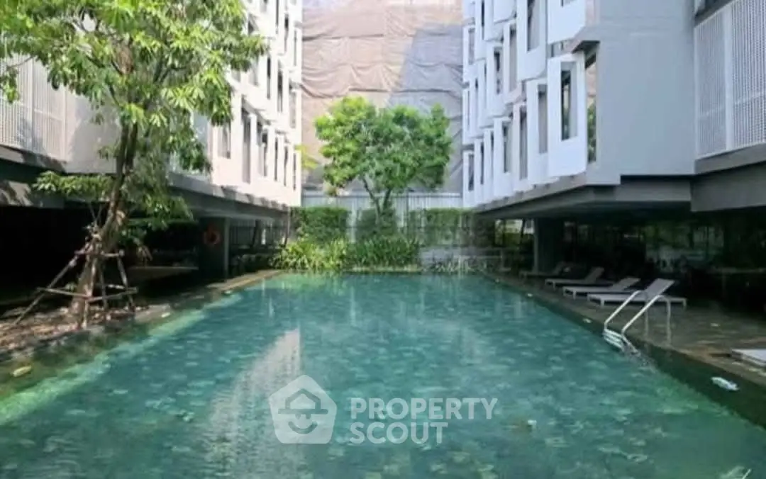 Luxurious modern apartment complex with serene swimming pool and lush greenery.