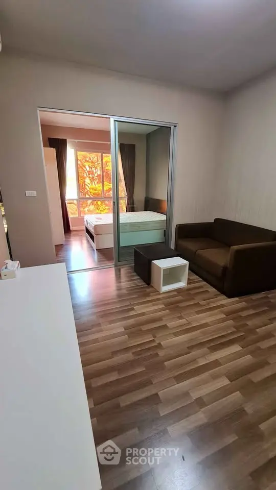 Modern apartment interior with cozy living room and bedroom, featuring wooden flooring and stylish furniture.