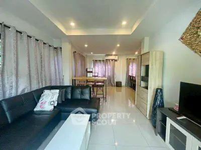 Spacious modern living room with sleek black sofa and elegant dining area.