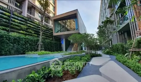 Modern residential complex with lush garden and pool area, showcasing contemporary architecture and serene outdoor space.