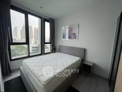 Modern bedroom with large windows and city view, featuring a comfortable bed and stylish decor.