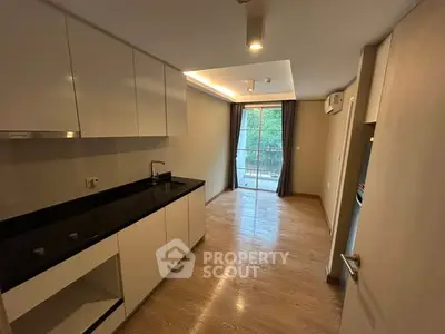 Modern kitchen with sleek cabinets and open layout leading to balcony