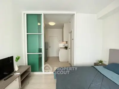 Modern studio apartment with sleek design and sliding glass partition, featuring cozy bedroom and compact kitchen.