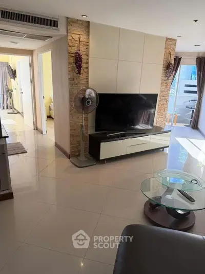 Modern living room with sleek TV unit and glass coffee table in a bright apartment