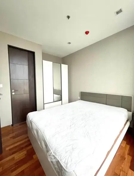 Modern bedroom with wooden flooring and sleek wardrobe in a contemporary apartment.