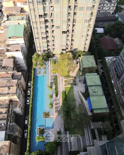 Stunning aerial view of modern apartment building with luxurious pool and lush garden.