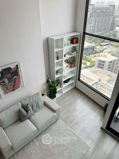 Modern living room with large window and city view, featuring stylish decor and cozy seating.