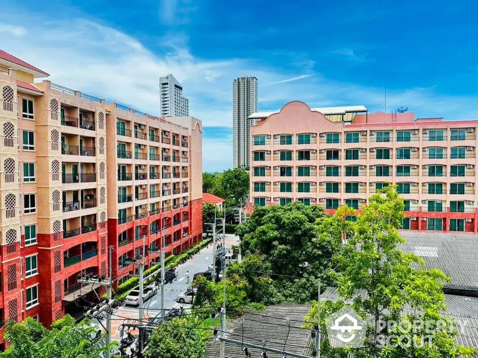 Vibrant urban apartment complex with lush greenery and clear blue sky view.