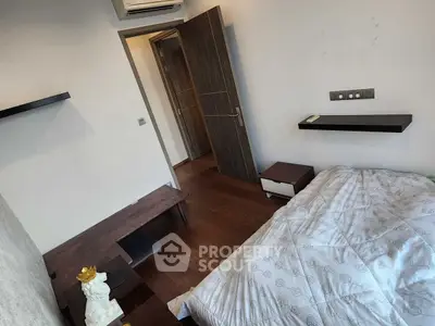 Cozy bedroom with modern decor and wooden flooring, featuring a comfortable bed and stylish shelving.