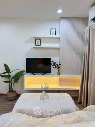 Modern bedroom with stylish decor, wall-mounted TV, and cozy lighting