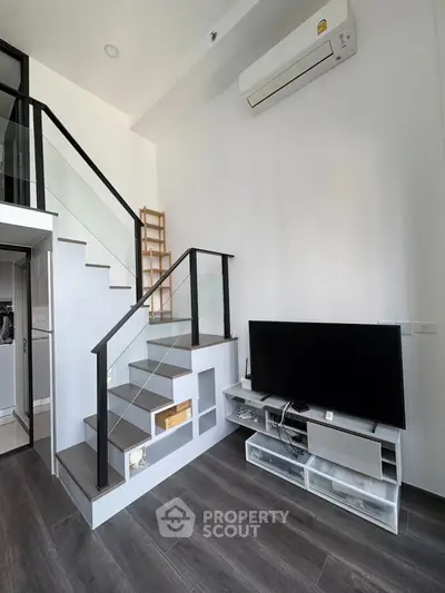 Modern duplex living room with sleek staircase and wall-mounted TV, perfect for urban living.