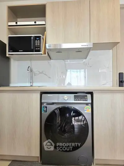 Modern kitchen with built-in appliances including washing machine and microwave, sleek cabinetry and backsplash.