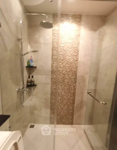 Modern bathroom with elegant shower design and decorative tile wall.