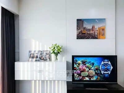 Modern living room with sleek white cabinet, vibrant wall art, and flat-screen TV displaying colorful coral reef.