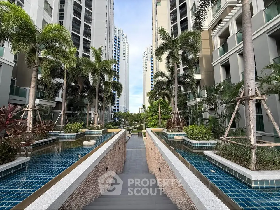 Luxurious condominium entrance with palm trees and water features, offering a serene urban oasis.