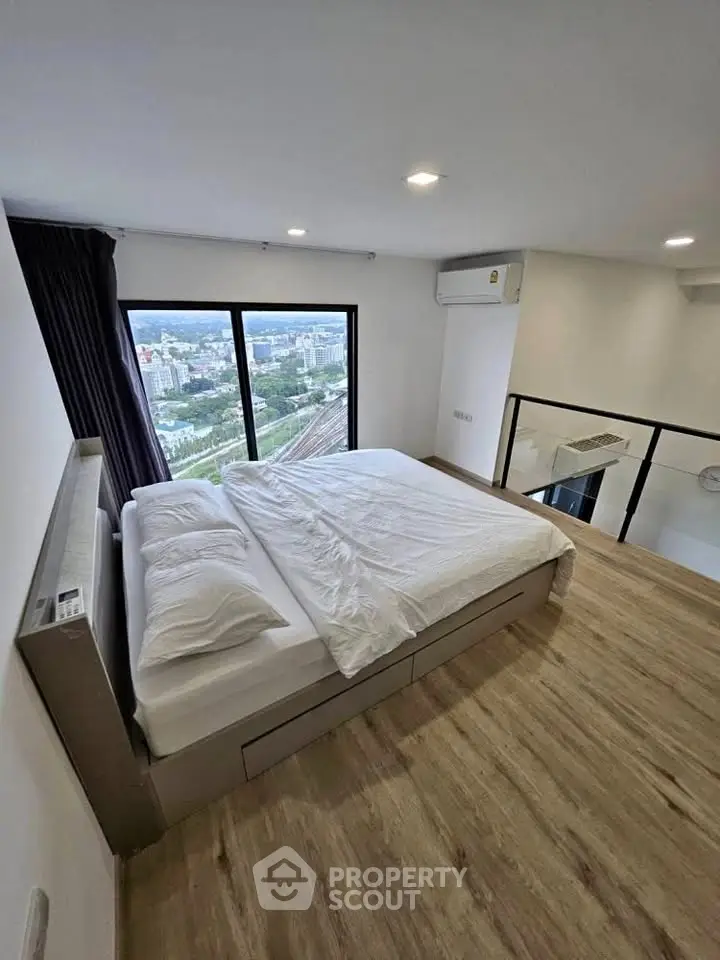 Modern bedroom with large window offering stunning city view, featuring sleek wooden flooring and minimalist design.