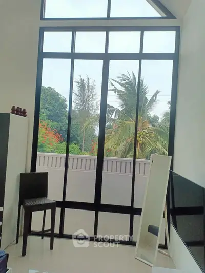 Spacious room with large windows offering lush garden views, perfect for natural light lovers.