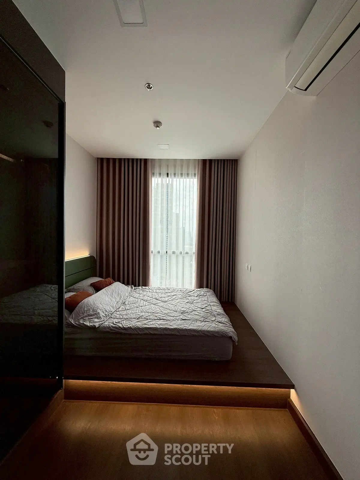 Modern bedroom with sleek design and ambient lighting, featuring a cozy bed and elegant curtains.