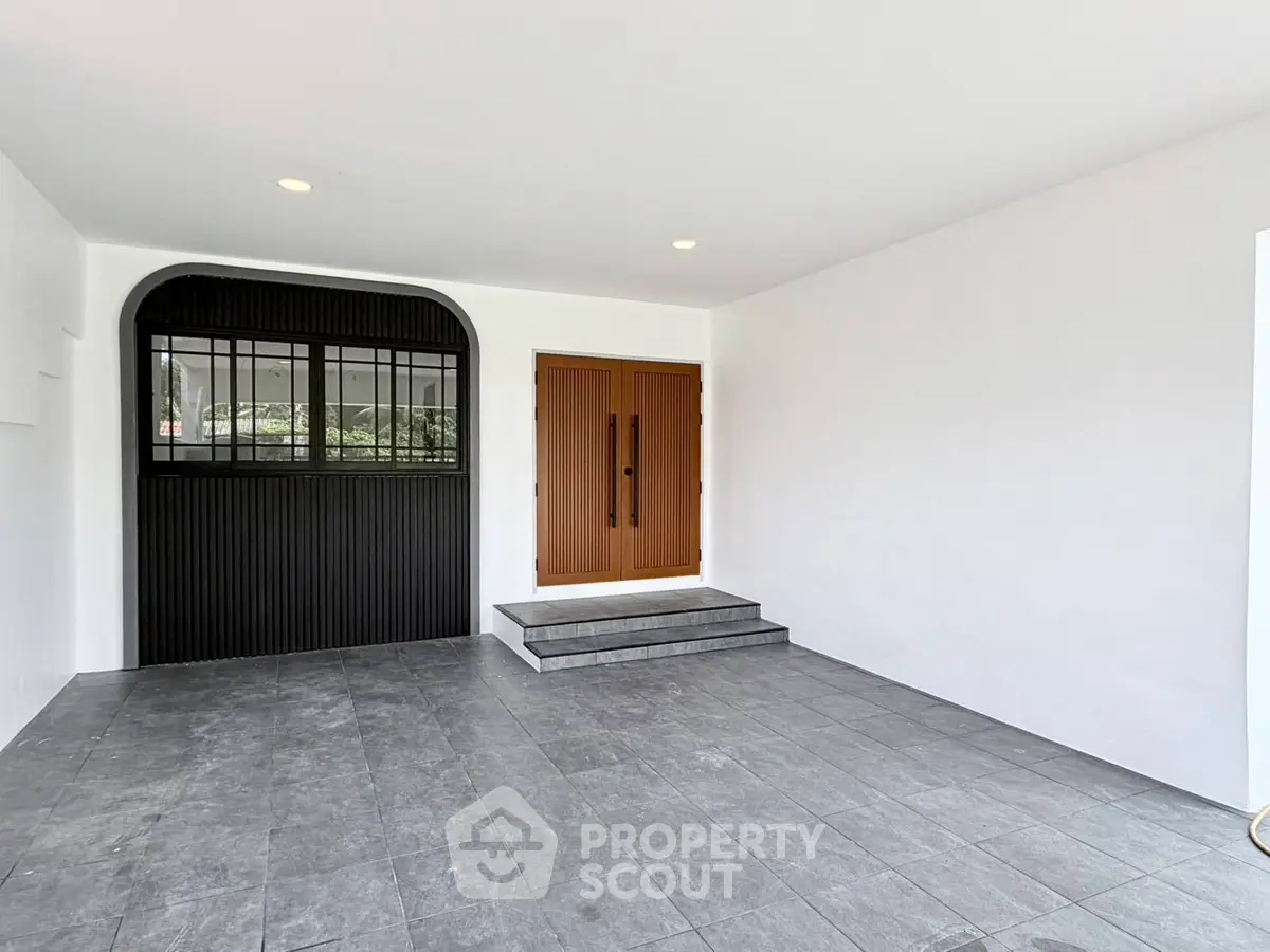 Modern entrance with sleek design and tiled flooring, featuring a stylish wooden door and black accent wall.