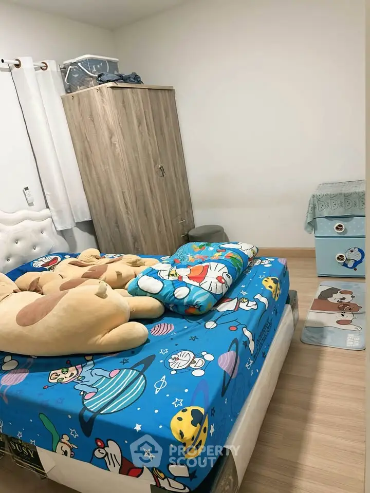 Cozy bedroom with playful cartoon-themed bedding and wooden wardrobe, perfect for a child's room.