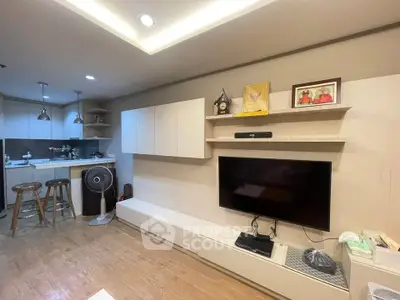Modern living room with open kitchen, featuring sleek cabinetry and cozy lighting.