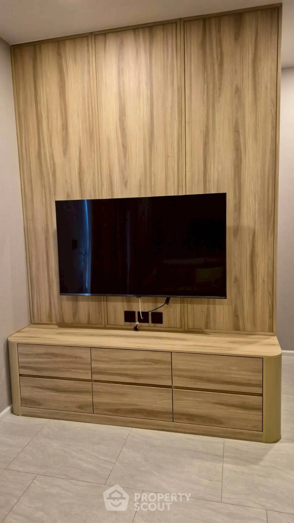 Modern living room with sleek wooden TV unit and mounted flat-screen television.