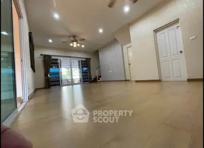 Spacious living room with wooden flooring and ceiling fan, ideal for family gatherings.