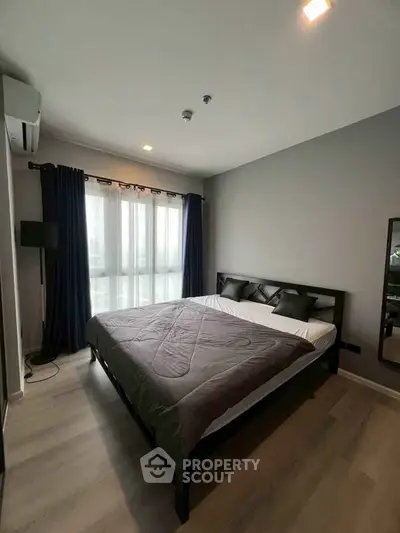 Modern bedroom with large window and stylish decor in a contemporary apartment.
