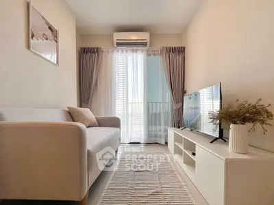 Modern living room with sleek sofa, TV unit, and large window offering natural light.