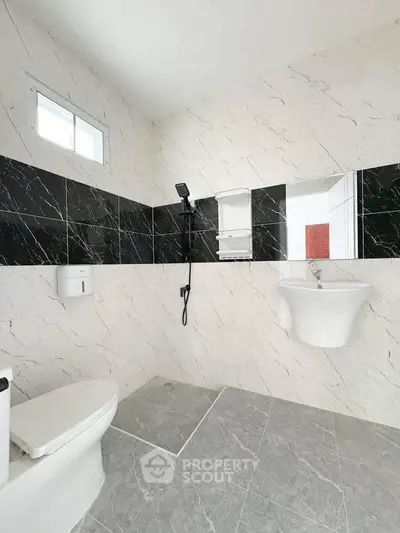 Modern bathroom with sleek black and white marble tiles and contemporary fixtures.