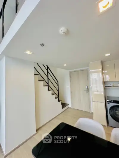 Modern duplex apartment with sleek staircase and in-unit washer in open kitchen layout.