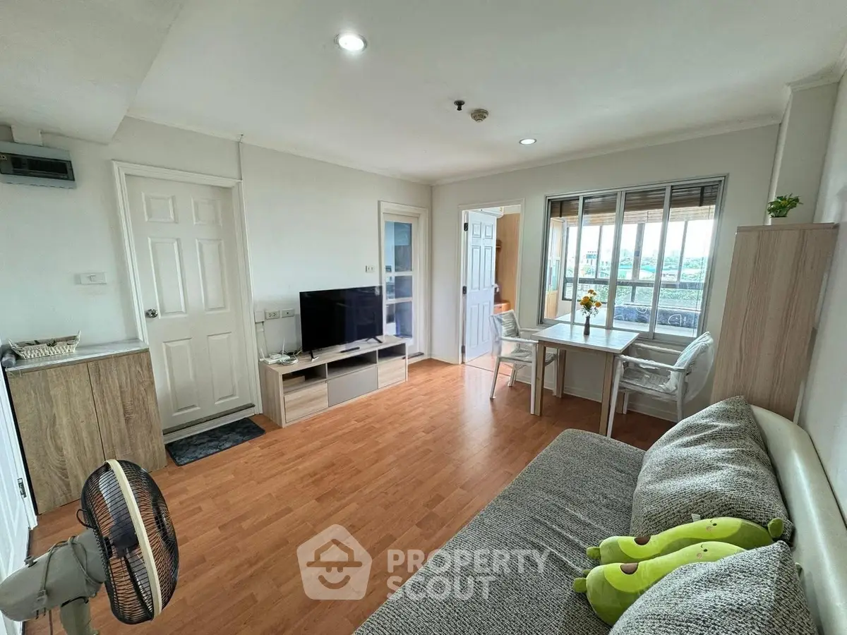 Bright and cozy living room with modern decor and wooden flooring, featuring a TV and dining area.