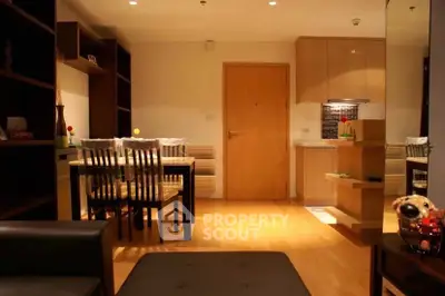 Cozy dining area with wooden furniture and modern kitchen in open layout apartment.