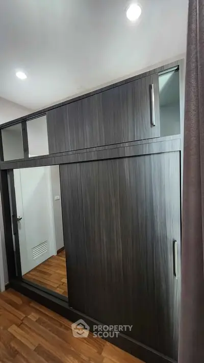 Modern wooden wardrobe with sliding doors and mirror in stylish bedroom
