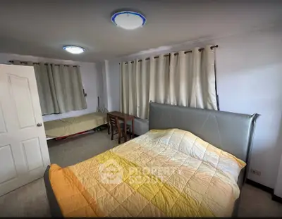 Cozy bedroom with modern bed and study area, featuring ample natural light and neutral decor.