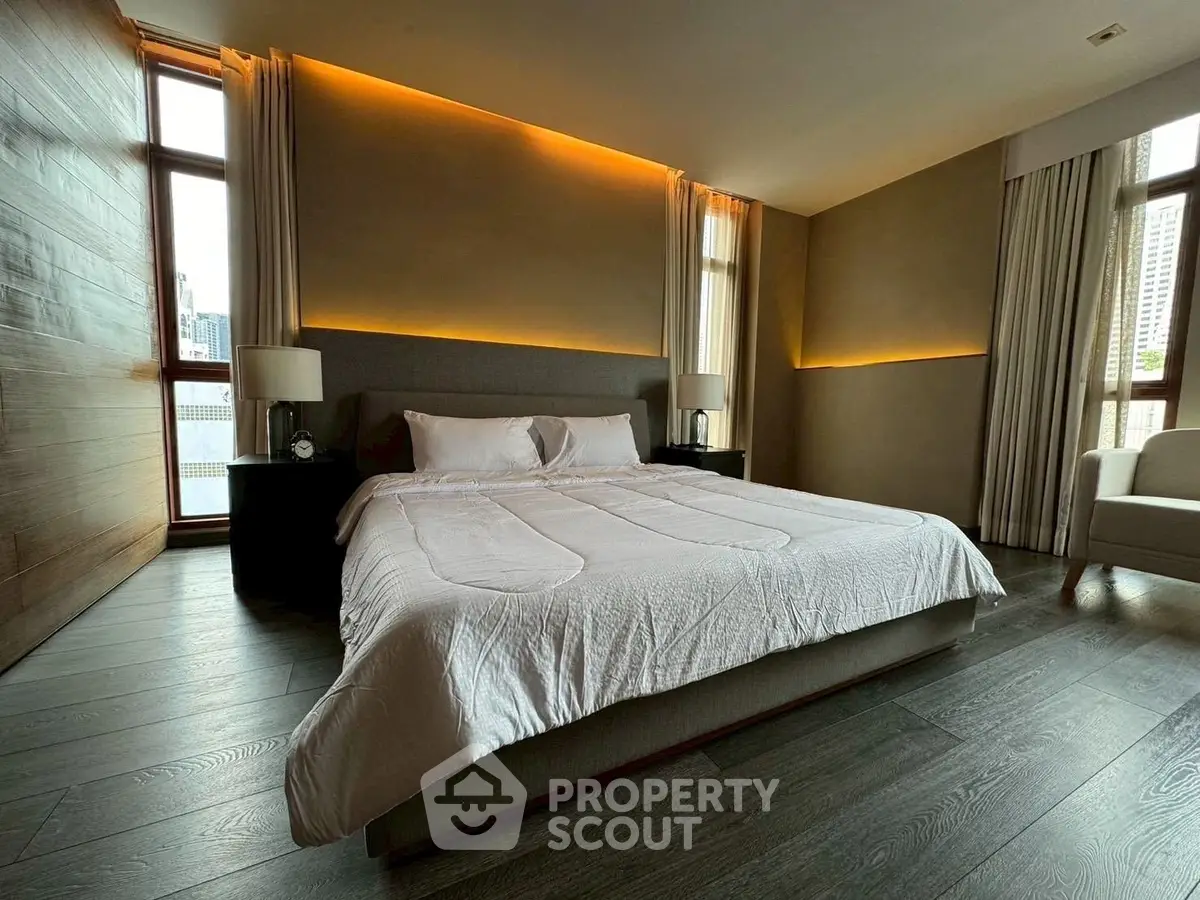 Luxurious bedroom with modern lighting and large windows in a high-rise apartment.