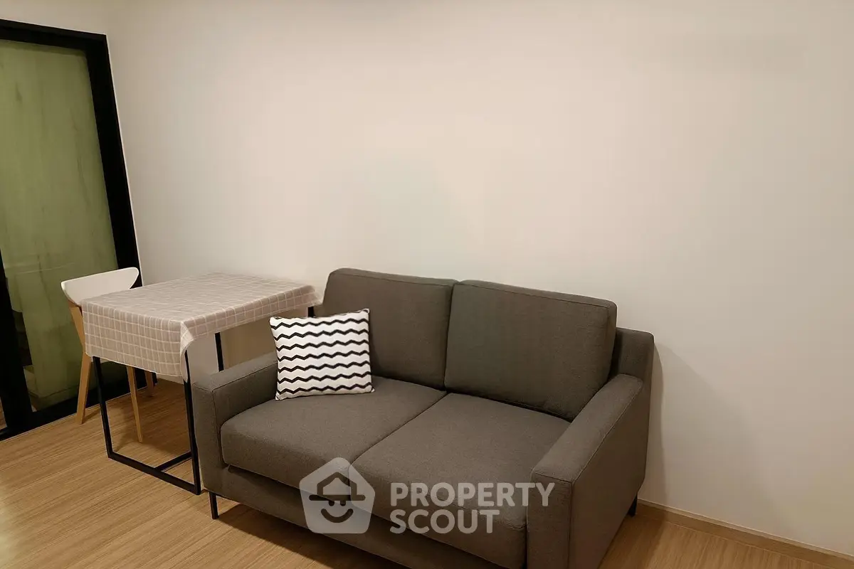 Cozy living room with modern gray sofa and stylish dining table in a compact space.