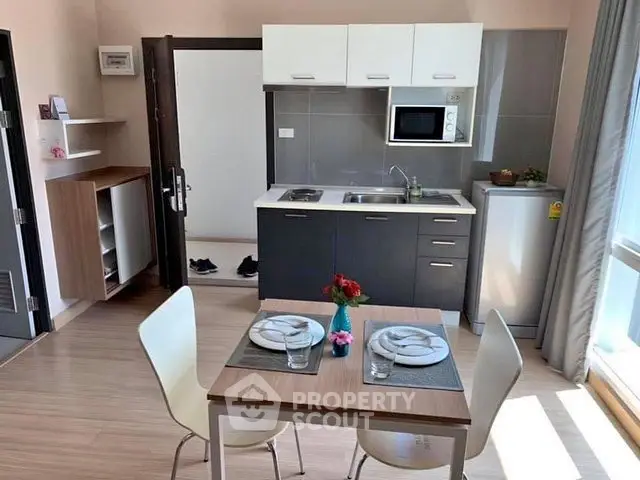 Modern kitchen with dining area, featuring sleek cabinetry and natural light.