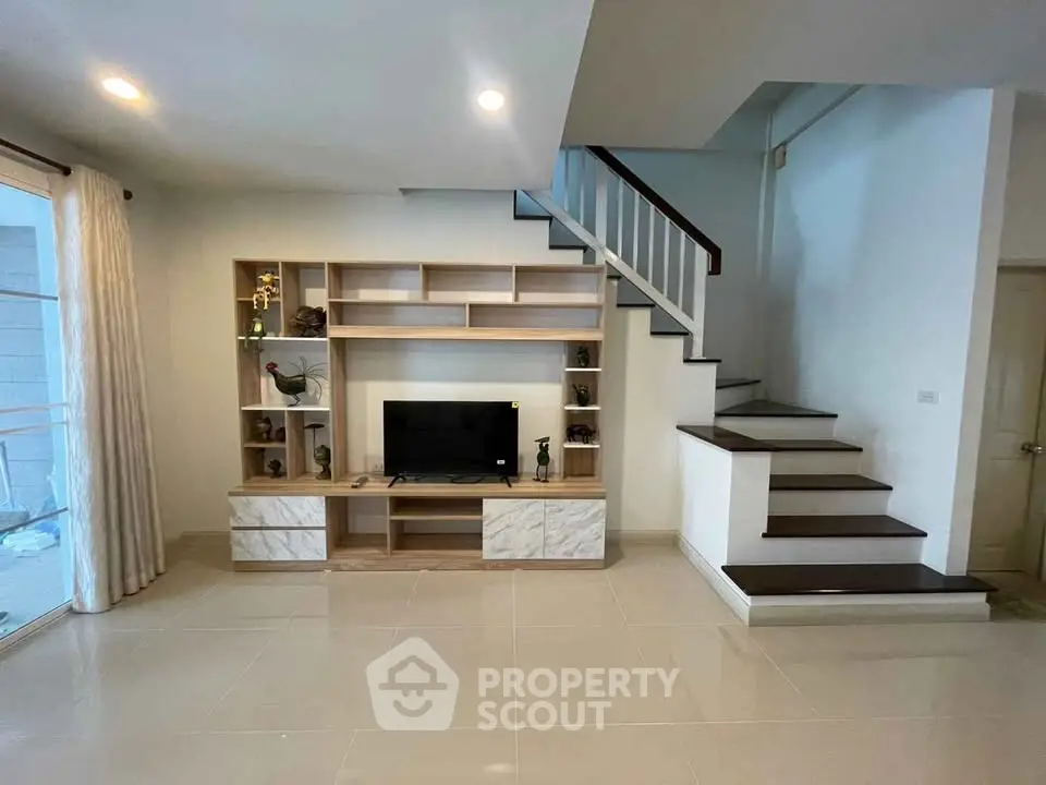 Modern living room with sleek staircase and built-in TV unit