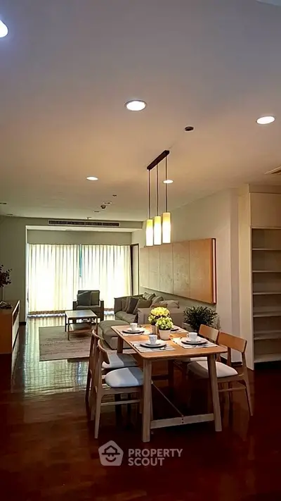 Spacious open-plan living and dining area with elegant lighting and wooden flooring.