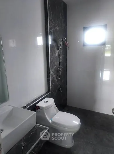 Modern bathroom with sleek design and elegant fixtures, featuring a stylish toilet and shower area.