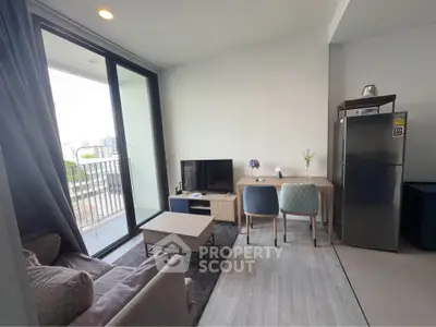 Modern living room with balcony view, stylish furniture, and sleek appliances in a contemporary apartment.