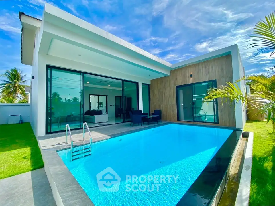 Luxurious modern villa with private pool and spacious outdoor area under clear blue sky.