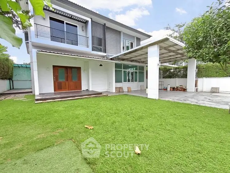 Spacious modern house with lush green lawn and covered patio, perfect for family gatherings.