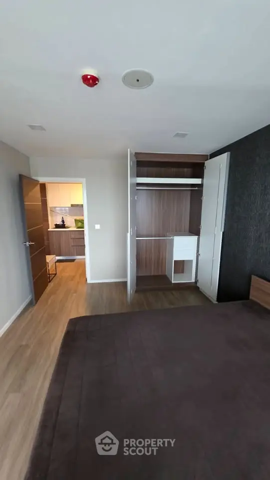 Spacious bedroom with open closet and view into modern kitchen