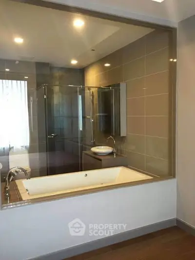 Luxurious bathroom with modern bathtub and glass shower enclosure in elegant apartment.