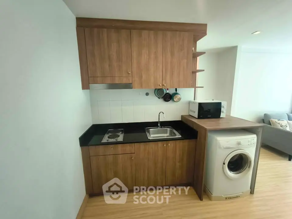Modern compact kitchen with wooden cabinets and washing machine in cozy apartment