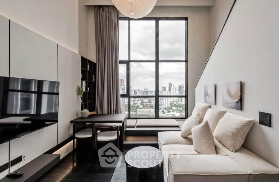 Modern living room with large window and city view, featuring sleek furniture and stylish decor.