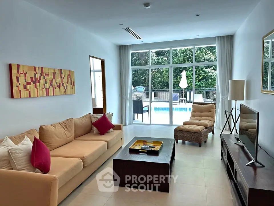Spacious living room with pool view, modern decor, and natural light