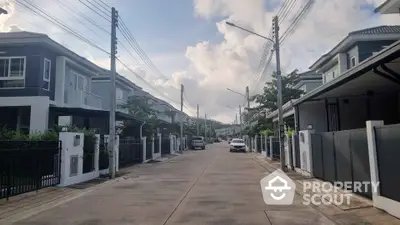 Charming suburban street with modern houses and lush greenery under a bright sky.